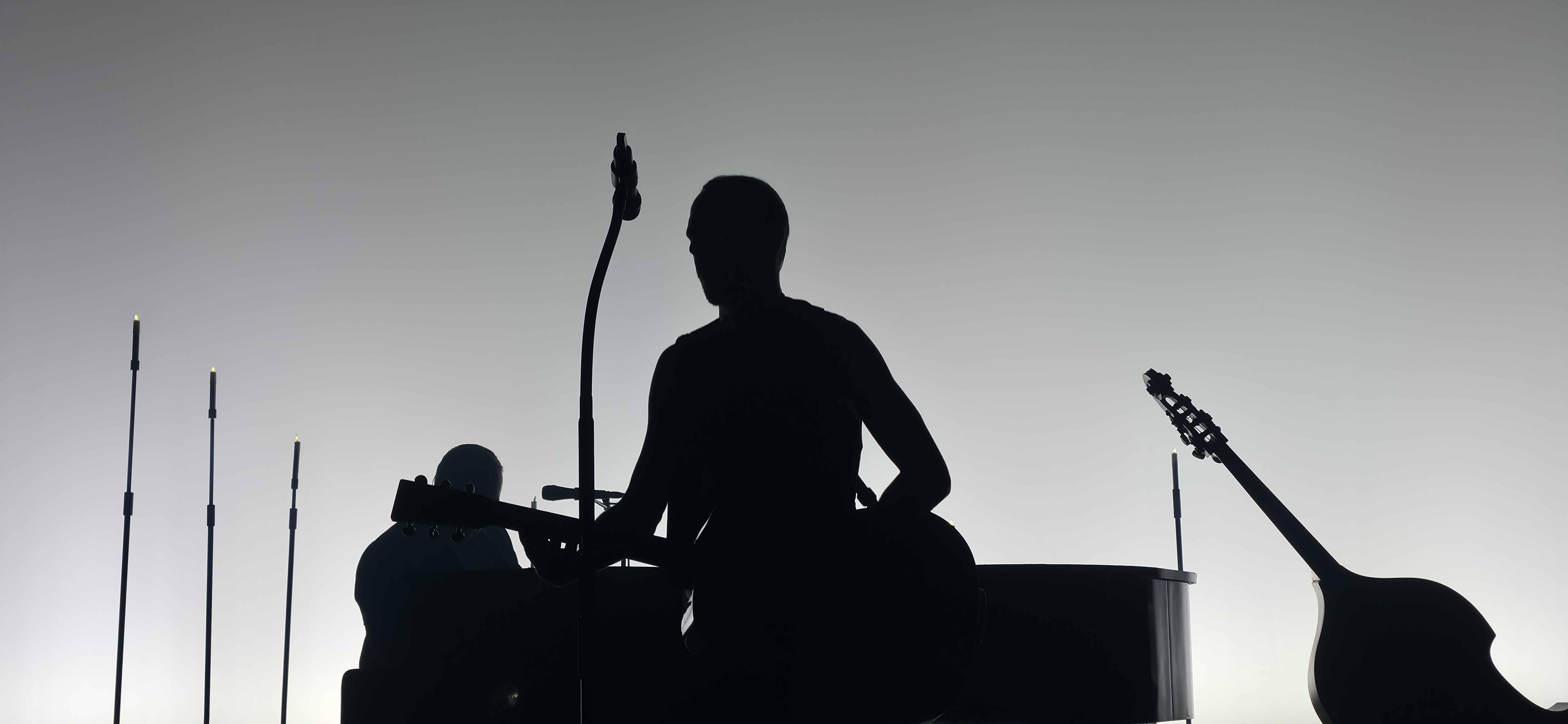Silhouette d’un musicien avec sa guitare sur une scène en contre-jour.
